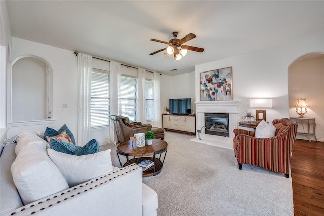 12067 Sunny St, Frisco, TX 75033 - living room with arched walkways, a ceiling fan, a glass covered fireplace, baseboards, and wood finished floors
