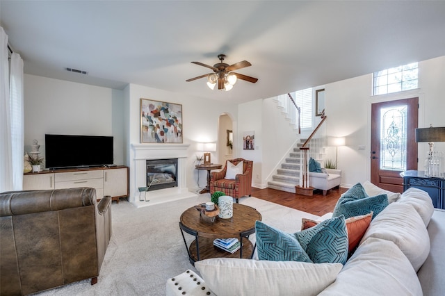 12067 Sunny St, Frisco, TX 75033 - living room featuring stairway, arched walkways, a glass covered fireplace, and a ceiling fan