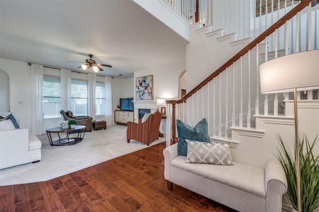 12067 Sunny St, Frisco, TX 75033 - carpeted living room with arched walkways, stairs, a glass covered fireplace, wood finished floors, and a high ceiling
