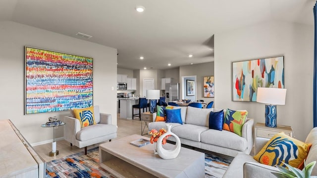 living area featuring baseboards, visible vents, recessed lighting, light wood-style floors, and lofted ceiling