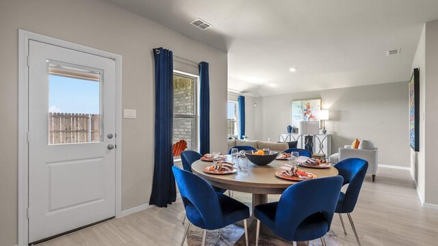 dining area with baseboards, light wood finished floors, visible vents, and plenty of natural light