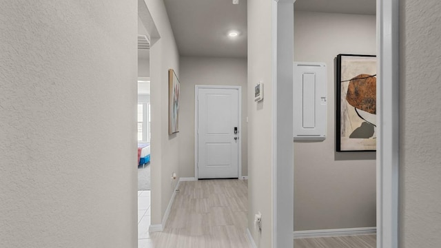 corridor featuring baseboards and electric panel