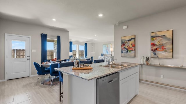 kitchen featuring recessed lighting, an island with sink, stainless steel dishwasher, a sink, and white cabinetry