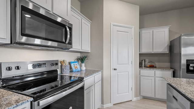 kitchen featuring white cabinets, stainless steel appliances, and light stone countertops