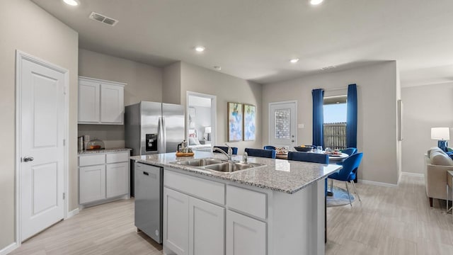 kitchen with a kitchen island with sink, a sink, open floor plan, visible vents, and appliances with stainless steel finishes