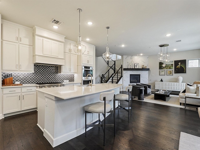 9136 Rock Daisy Ct, Dallas, TX 75231 - kitchen featuring a high end fireplace, dark wood-type flooring, open floor plan, white cabinets, and recessed lighting