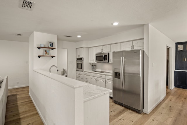 1764 Brown Trl, Hurst, TX 76054 - kitchen with appliances with stainless steel finishes, white cabinets, a peninsula, baseboards, and light wood-style flooring