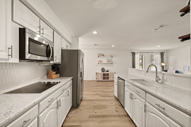 1764 Brown Trl, Hurst, TX 76054 - kitchen with appliances with stainless steel finishes, a sink, light wood-type flooring, recessed lighting, and white cabinetry