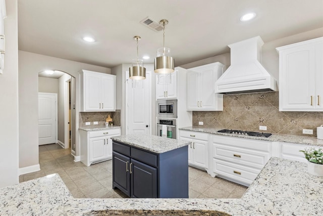 kitchen featuring custom exhaust hood, arched walkways, appliances with stainless steel finishes, and white cabinetry