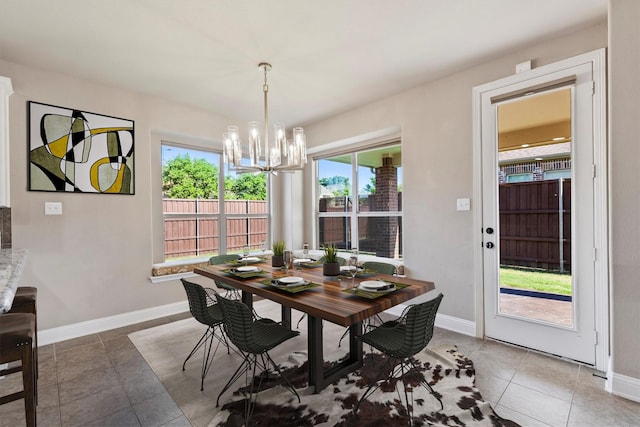 tiled dining room featuring baseboards and an inviting chandelier