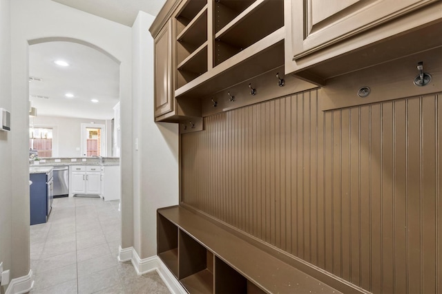 mudroom with a sink, arched walkways, recessed lighting, and light tile patterned floors