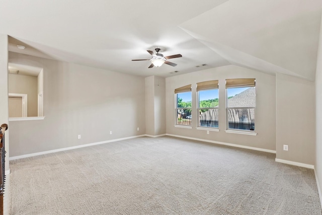 carpeted spare room featuring vaulted ceiling, visible vents, baseboards, and ceiling fan