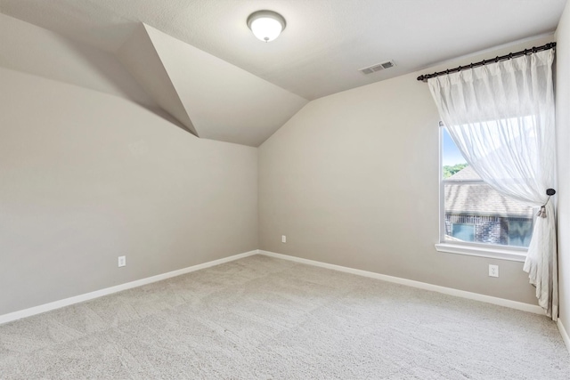 additional living space with vaulted ceiling, carpet floors, visible vents, and baseboards