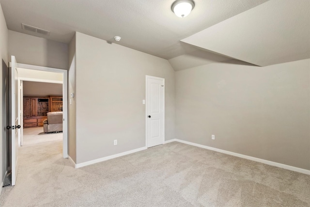 bonus room featuring light colored carpet, baseboards, lofted ceiling, and visible vents
