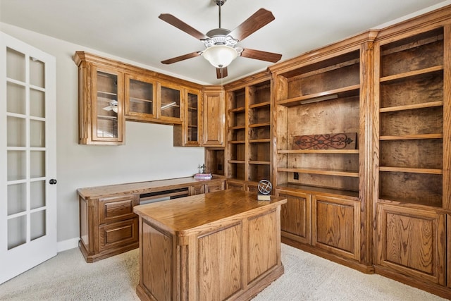 office space with ceiling fan, built in study area, and light colored carpet