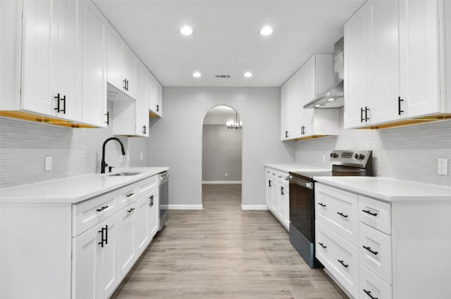 6709 Santiago Ave, Fort Worth, TX 76133 - kitchen with appliances with stainless steel finishes, wall chimney exhaust hood, a sink, arched walkways, and baseboards