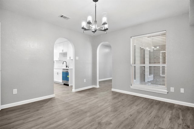 6709 Santiago Ave, Fort Worth, TX 76133 - empty room featuring arched walkways, dark wood finished floors, a chandelier, a sink, and baseboards