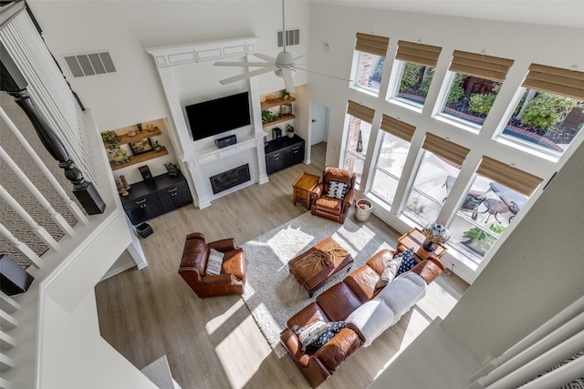 living area with visible vents, wood finished floors, a high ceiling, and ceiling fan