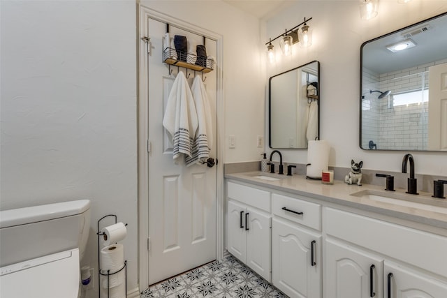 bathroom with double vanity, toilet, walk in shower, and a sink