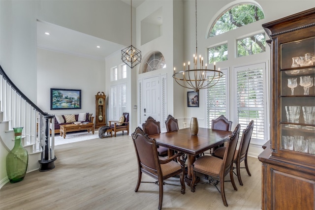 dining area featuring a high ceiling, a notable chandelier, light wood finished floors, and a wealth of natural light