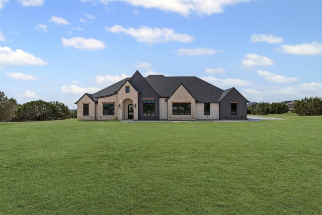 7103 Heathington Ct, Granbury, TX 76049 - french country home featuring a front lawn, board and batten siding, and brick siding