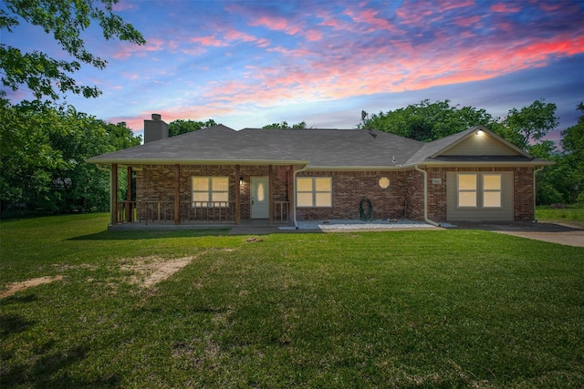 single story home featuring a porch, a chimney, brick siding, and a front yard