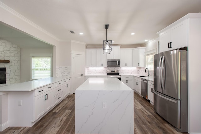 kitchen featuring stainless steel appliances, a peninsula, a sink, decorative backsplash, and a kitchen island