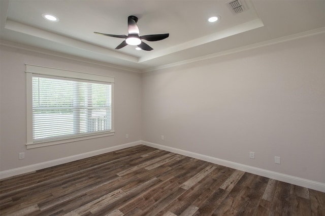 spare room featuring a ceiling fan, dark wood-type flooring, visible vents, and a raised ceiling