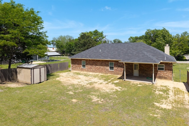 back of house featuring a storage shed, a chimney, a fenced backyard, a yard, and brick siding
