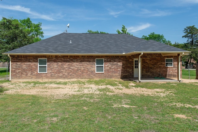 back of house with a lawn, brick siding, a patio, and a shingled roof