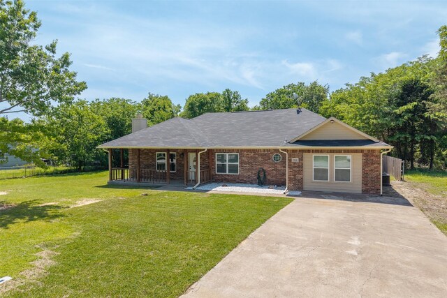 view of front of property with a chimney, a front lawn, driveway, and brick siding