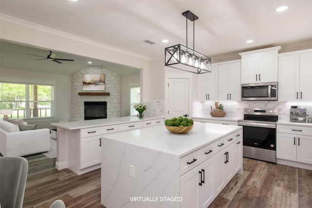 kitchen with decorative backsplash, open floor plan, stainless steel appliances, a peninsula, and visible vents