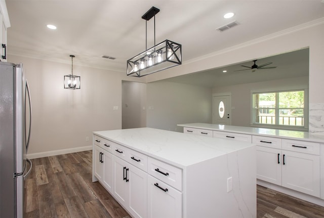 kitchen with a center island, dark wood finished floors, visible vents, freestanding refrigerator, and crown molding