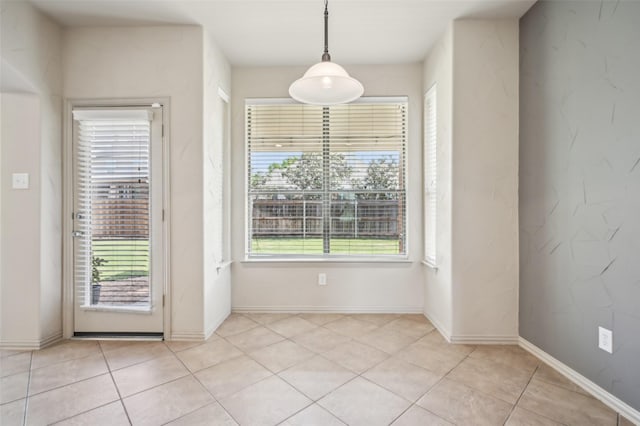 unfurnished dining area featuring baseboards and light tile patterned floors