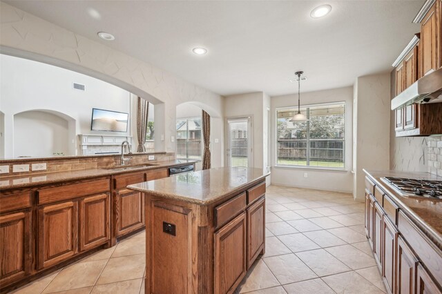 kitchen with a sink, visible vents, stainless steel gas stovetop, light stone counters, and brown cabinetry