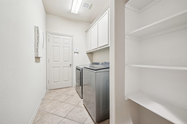 clothes washing area featuring visible vents, light tile patterned floors, baseboards, washer and dryer, and cabinet space