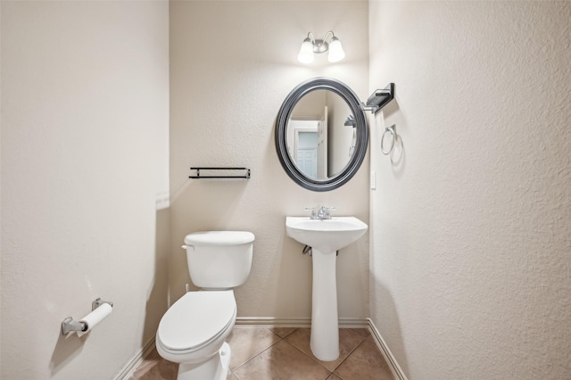 half bathroom with toilet, tile patterned floors, and baseboards