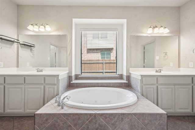 full bathroom featuring two vanities, a tub with jets, and a sink