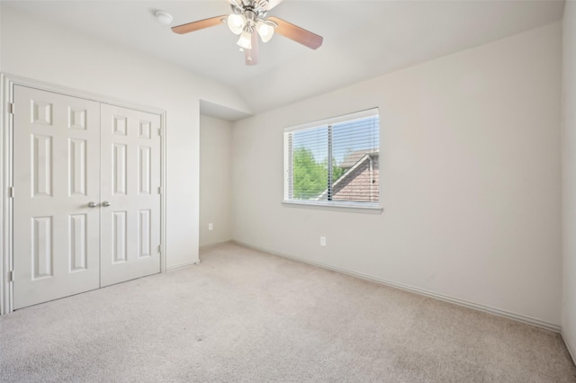 unfurnished bedroom with vaulted ceiling, a ceiling fan, a closet, baseboards, and carpet flooring