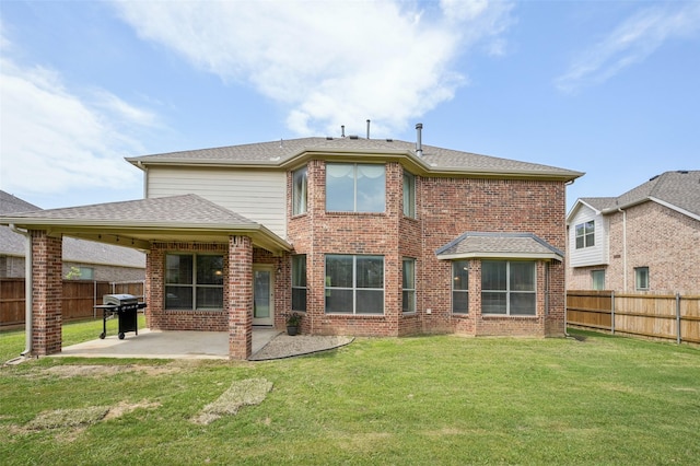 rear view of house with brick siding, a lawn, a fenced backyard, and a patio