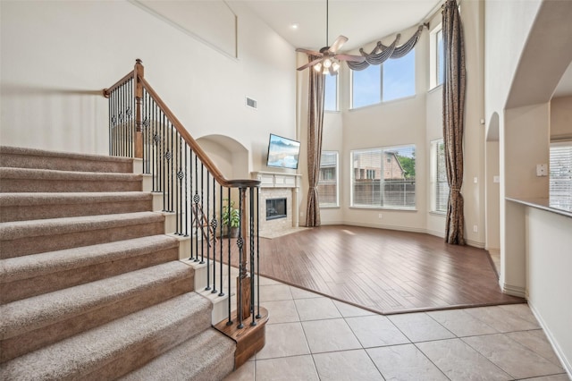 9616 Barksdale Dr, Fort Worth, TX 76244 - stairs featuring ceiling fan, a fireplace, tile patterned floors, baseboards, and a high ceiling