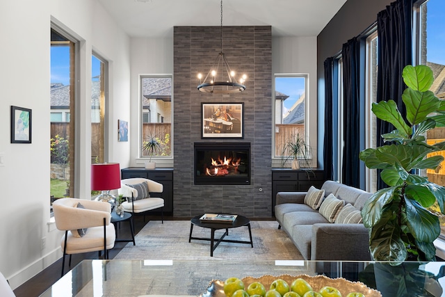 interior space featuring wood finished floors, a tiled fireplace, baseboards, and an inviting chandelier