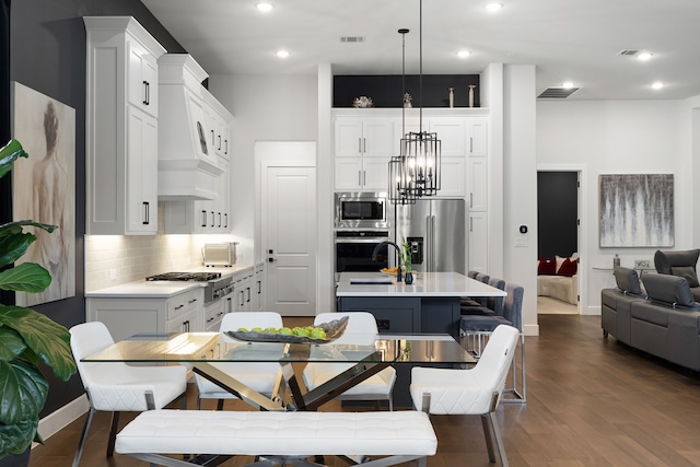 kitchen featuring an island with sink, stainless steel appliances, light countertops, a sink, and tasteful backsplash