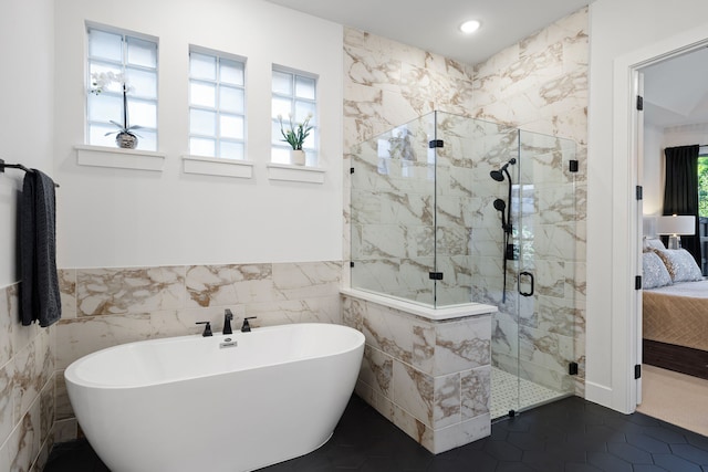 ensuite bathroom featuring a freestanding bath, tile walls, wainscoting, a shower stall, and connected bathroom