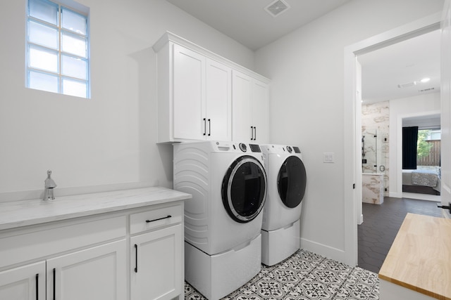 washroom with washer and dryer, baseboards, cabinet space, and visible vents