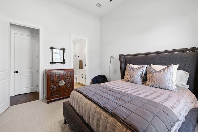 carpeted bedroom featuring vaulted ceiling, visible vents, and ensuite bathroom