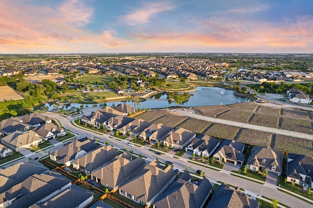aerial view at dusk with a residential view and a water view