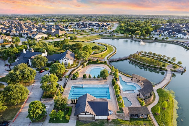 aerial view at dusk featuring a residential view and a water view