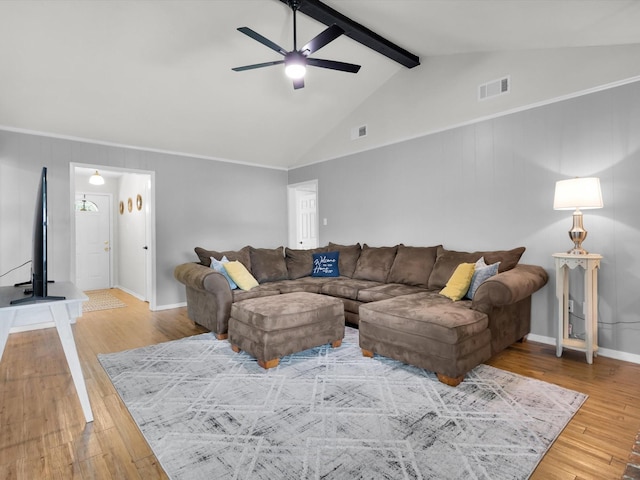 living area with a ceiling fan, visible vents, vaulted ceiling with beams, and hardwood / wood-style floors