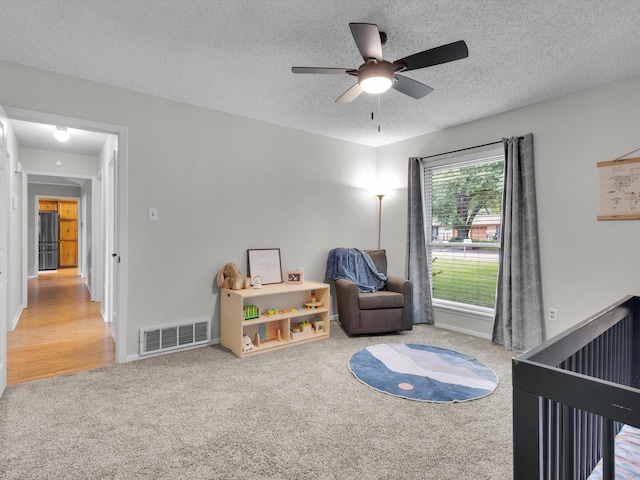 bedroom featuring carpet flooring, a textured ceiling, visible vents, and freestanding refrigerator